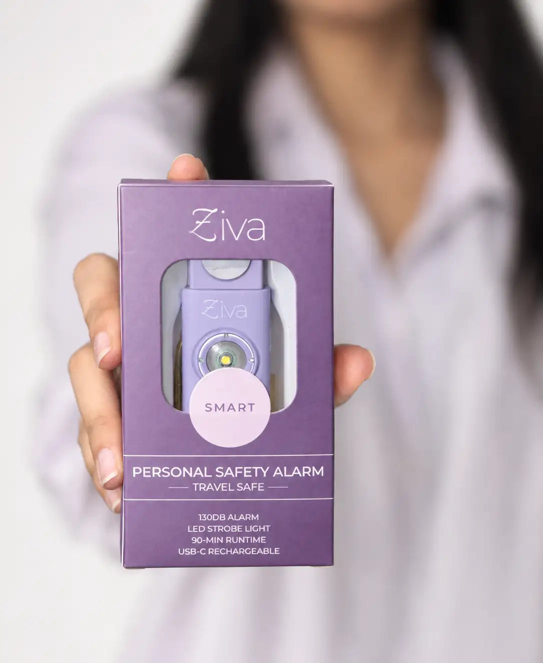 Hand holding the boxed Ziva Safety Alarm in lavender