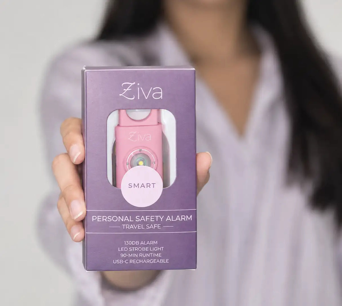 Hand holding the boxed Ziva Safety Alarm in pink
