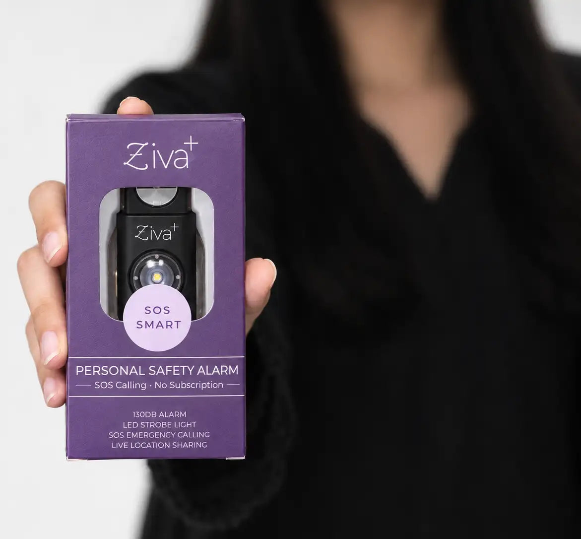 Hand holding the boxed Ziva+ SOS Safety Alarm in black