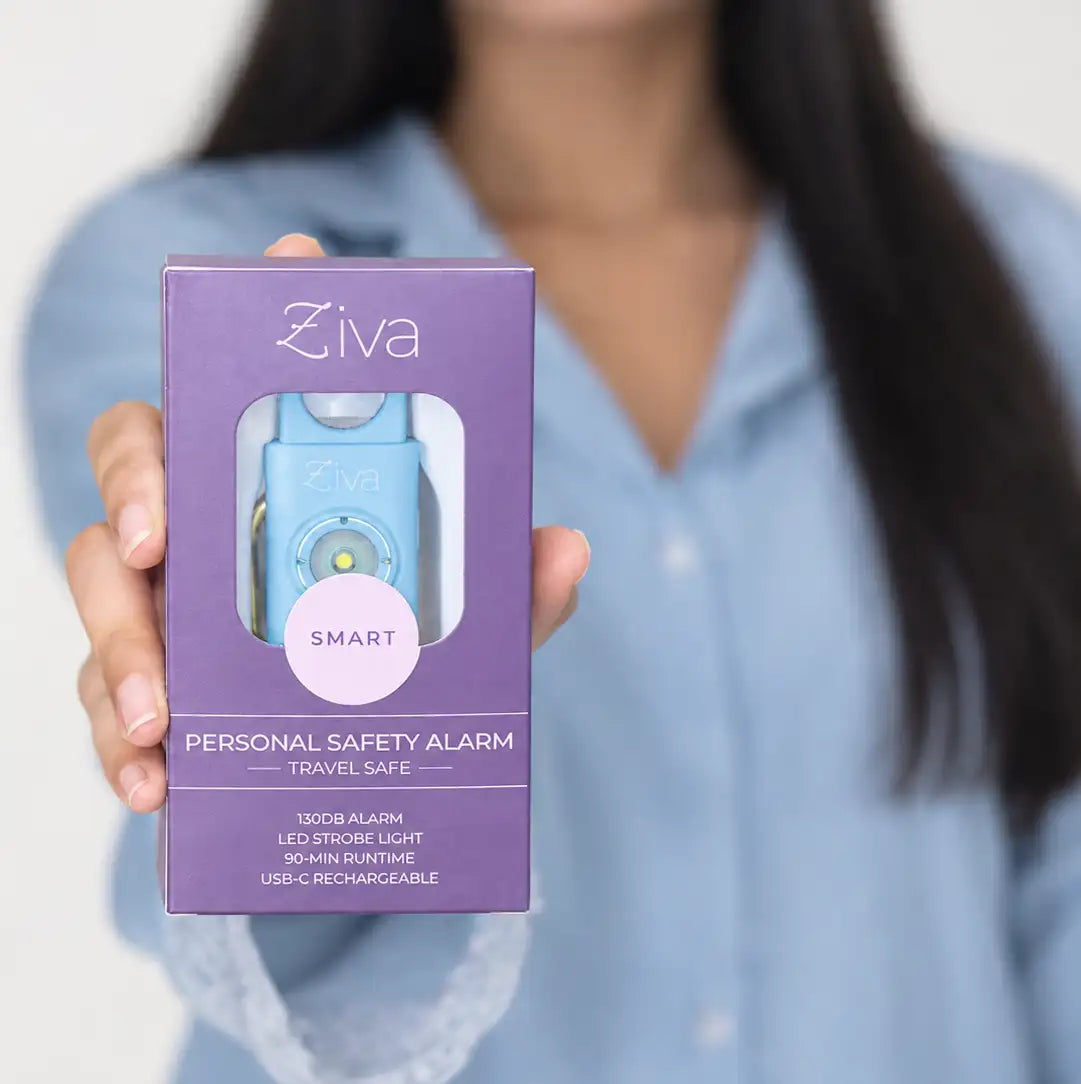 Hand holding the boxed Ziva Safety Alarm in sky blue